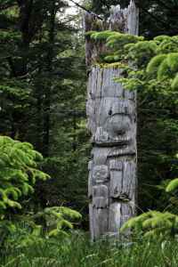 An ancient Haida mortuary totem at SGang Gwaay llnagaay (Ninstints) depicting a grizzly bear and a human infant, Gwaii Haanas. Photo by Brodie Guy. 