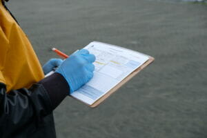 close up photo of someone wearing gloves and writing on a clipboard