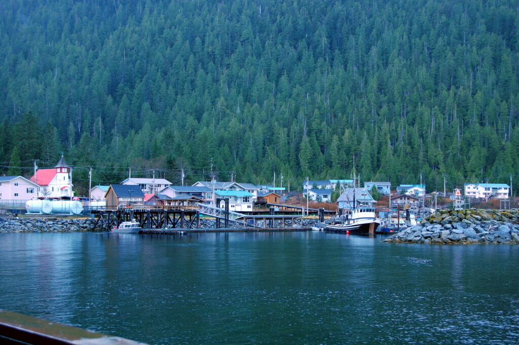view from the water of a small coasta =l community surrounded by forested mountains