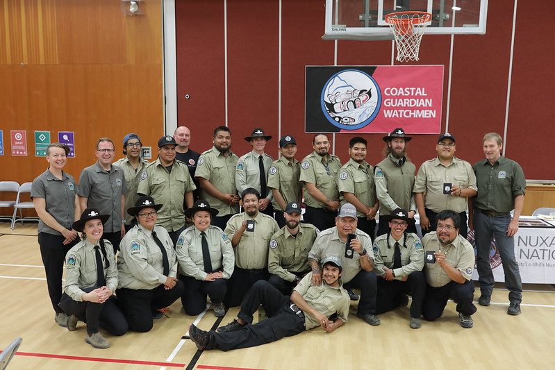 group of people dressed in Guardian and park ranger uniforms pose for a group photo in a gymnasium