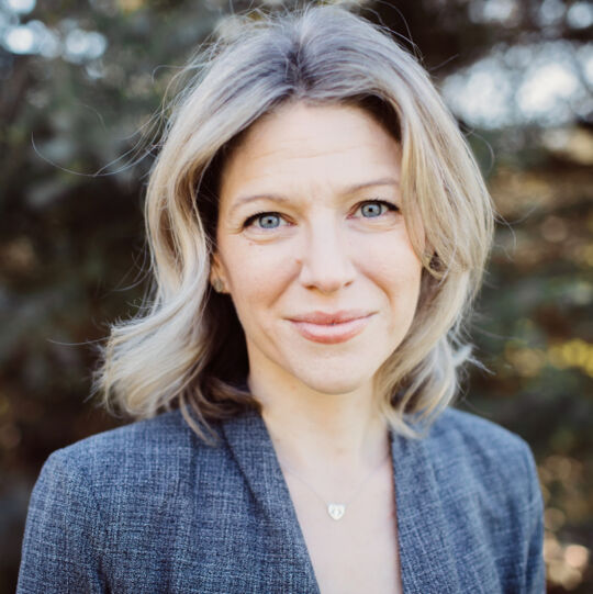 tamara isaak - professional photo of a woman with shoulder-length blonde hair wearing a grey suit jacket