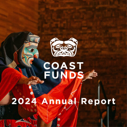 The cover image for the Coast Funds 2024 Annual Report shows a First Nations person dressed in regalia performing at a ceremony. Their regalia is a mix of bright reds, deep blues and black. They are wearing a large mask that is painted with a kaleidoscope of teal, blue, orange, red, and black. The Coast Funds logo, which is the face of a bear, is superimposed on top of the image in white.