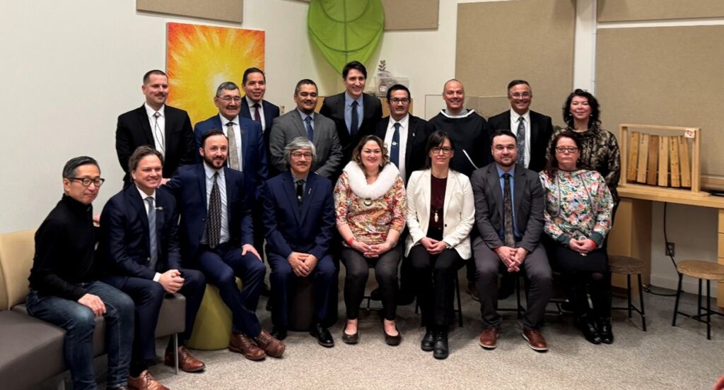 A group of people are seated for a photograph celebrating the signing of the SINAA agreement. Majority of people in the photo are wearing business attire. They are smiling and look relaxed. 