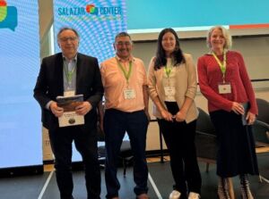The four PFP representatives: Lawrence, Olayuk, Dahti, and Darcy stand together just off stage. They are all smiling and look very bright and happy.