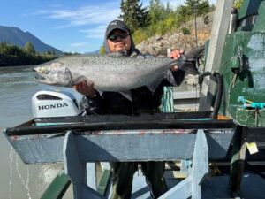 Technician Ben Gonu Jr holding an operculum and radio tagged Nass River Chinook salmon.