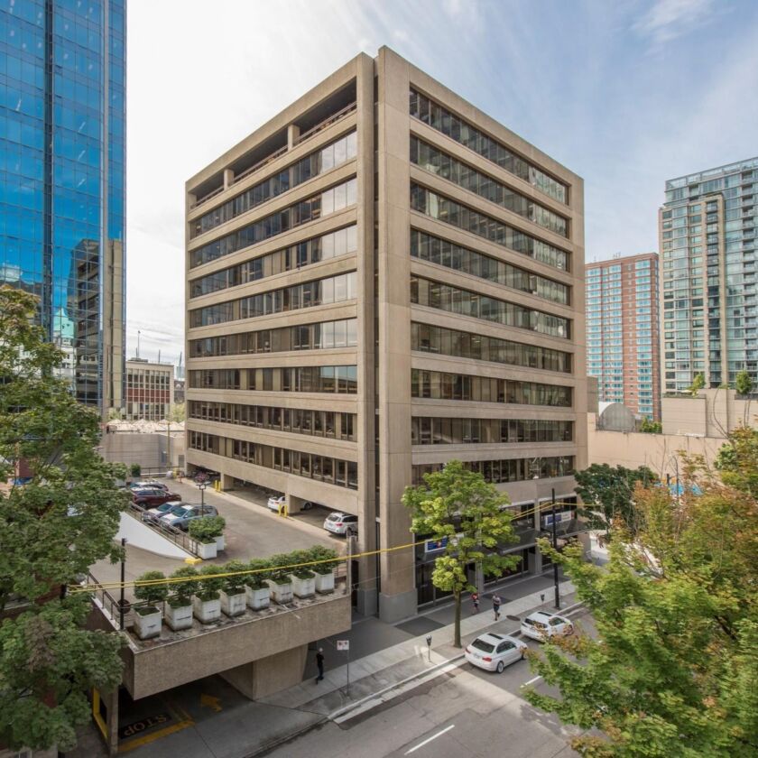 A photograph of a office building. The building is brown and in a classic square shape. It's about 10 floors high.