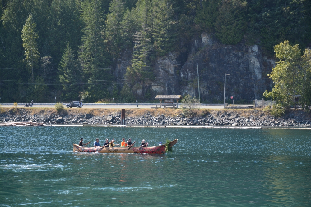 A canoe is paddled by eight people along the water.