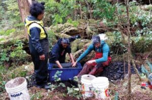 People stand around a site of excavated soil. 
